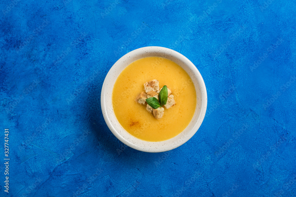 Pumpkin and carrot soup with cream and spinach with crackers on a classic blue background. Pumpkin and carrot soup with cream and spinach with crackers on a classic blue background.