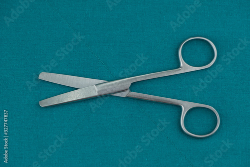 Basic surgical instrument stainless steel Straight operation scissors b/b isolated on surgical green drape fabric