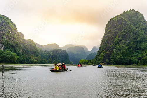 Tam Coc National Park - Tourists traveling in boats along the Ngo Dong River at Ninh Binh Province, Trang An landscape complex, Vietnam - Landscape formed by karst towers and rice fields