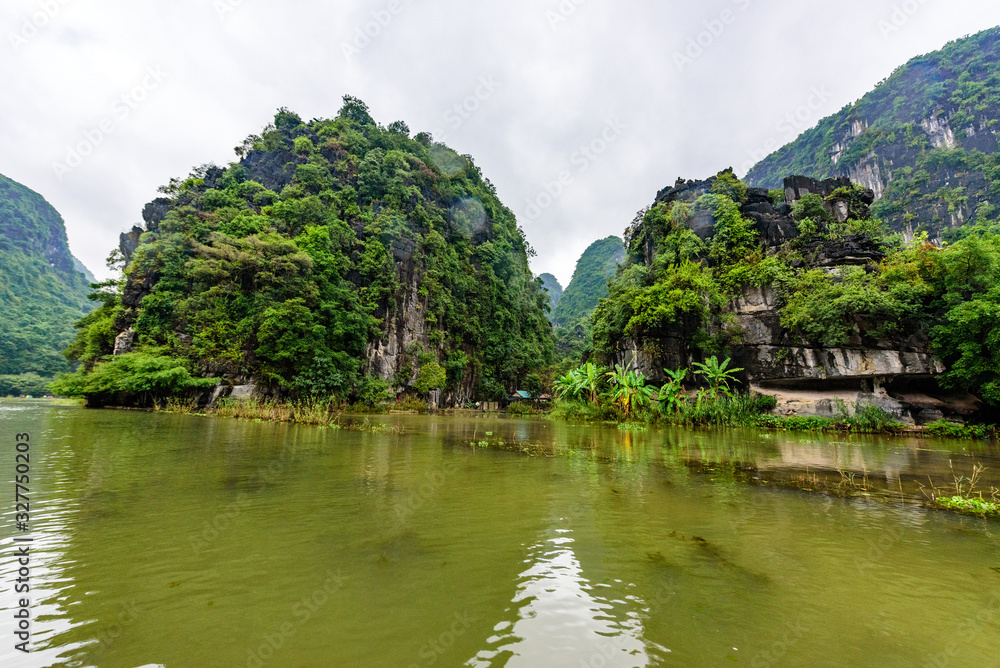 Tam Coc National Park - Tourists traveling in boats along the Ngo Dong River at Ninh Binh Province, Trang An landscape complex, Vietnam - Landscape formed by karst towers and rice fields Tam Coc National Park - Tourists traveling in boats along the Ngo Dong River at Ninh Binh Province, Trang An landscape complex, Vietnam - Landscape formed by karst towers and rice fields