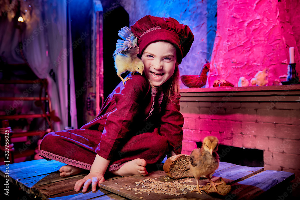 Small girl with little chicken in village interior in the room with wooden table. Easter, holiday and child concept Small girl with little chicken in village interior in the room with wooden table. Easter, holiday and child concept