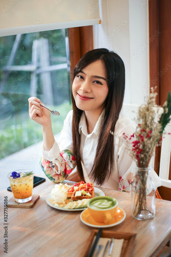 Beautiful asian woman eating delicious  waffles in coffee shop cafe.