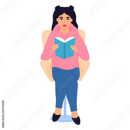 A teenager sits in a chair and reads a paper book. Schoolgirl preparing for the exam. Literature fans. Love reading.