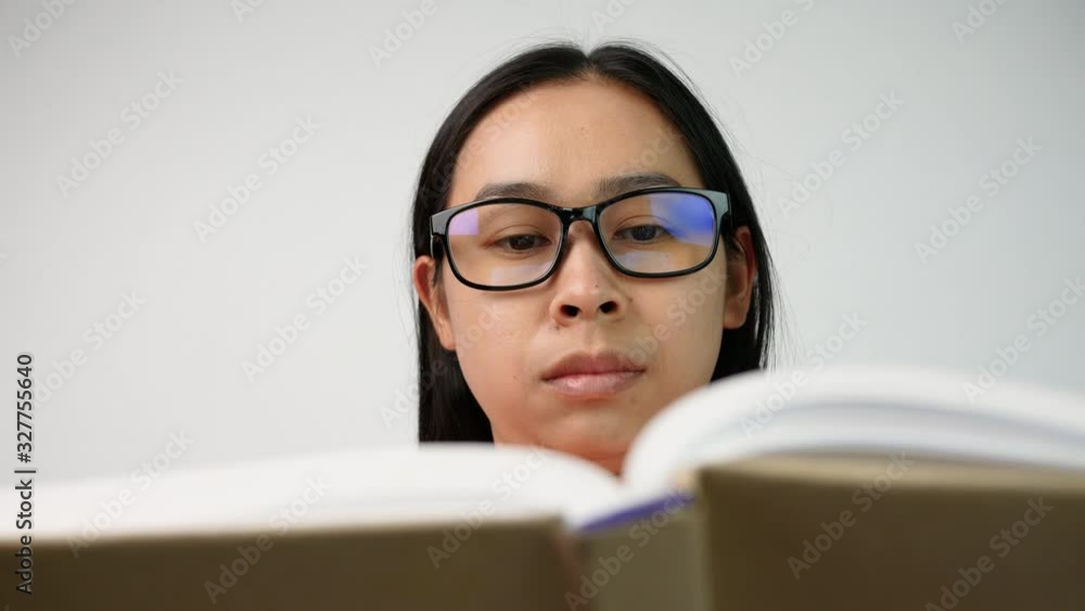 Close up of Woman's hand turning pages of a book and moves her fingers along the page while reading at library. Selective focus. Close up of Woman's hand turning pages of a book and moves her fingers along the page while reading at library. Selective focus.