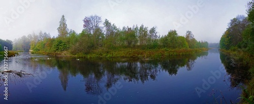 Panorama with a mirror reflection of the forest in the river