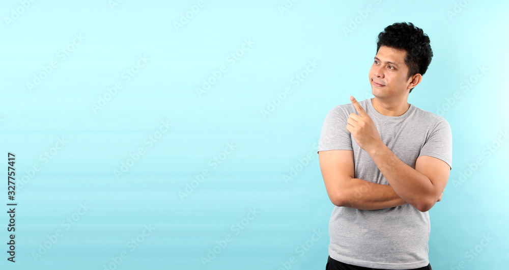Portrait of handsome,Shock and surprise face of asian man Pointing finger on empty space isolated on blue background in studio With copy space.