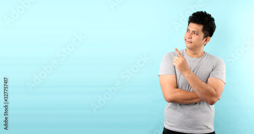 Portrait of handsome,Shock and surprise face of asian man Pointing finger on empty space isolated on blue background in studio With copy space. © Justinboat29