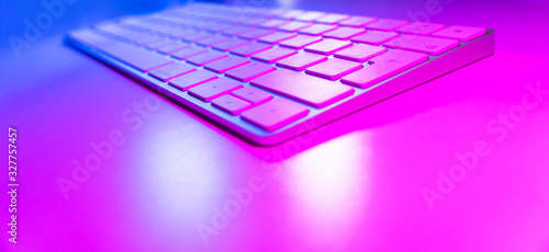 Close up view of a modern laptop computer keyboard keys. Soft lightning. Computer keyboard close up in pink and blue tones