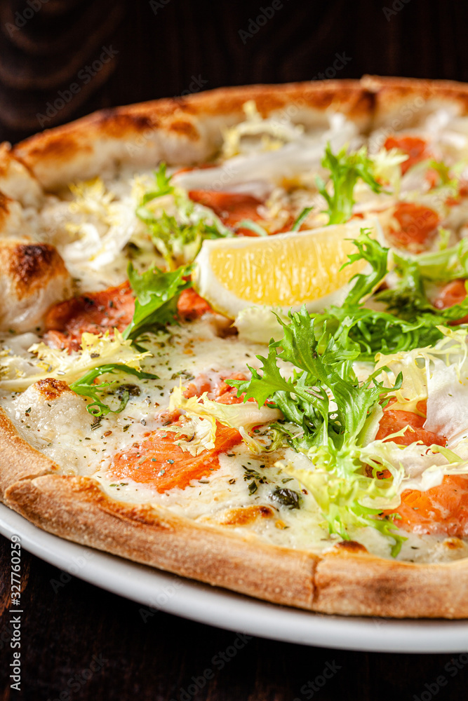 Italian cuisine. Thin pizza with large sides. Pizza with salmon, cheese sauce, lettuce. background image, copy space text Italian cuisine. Thin pizza with large sides. Pizza with salmon, cheese sauce, lettuce. background image, copy space text