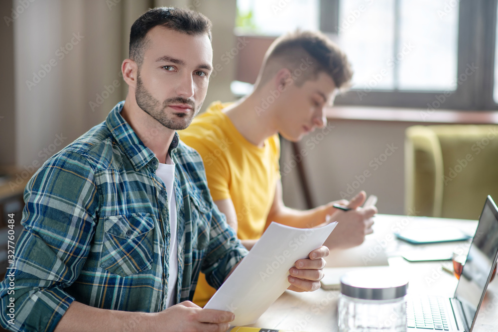 Two young men working together on the project and looking serious Two young men working together on the project and looking serious