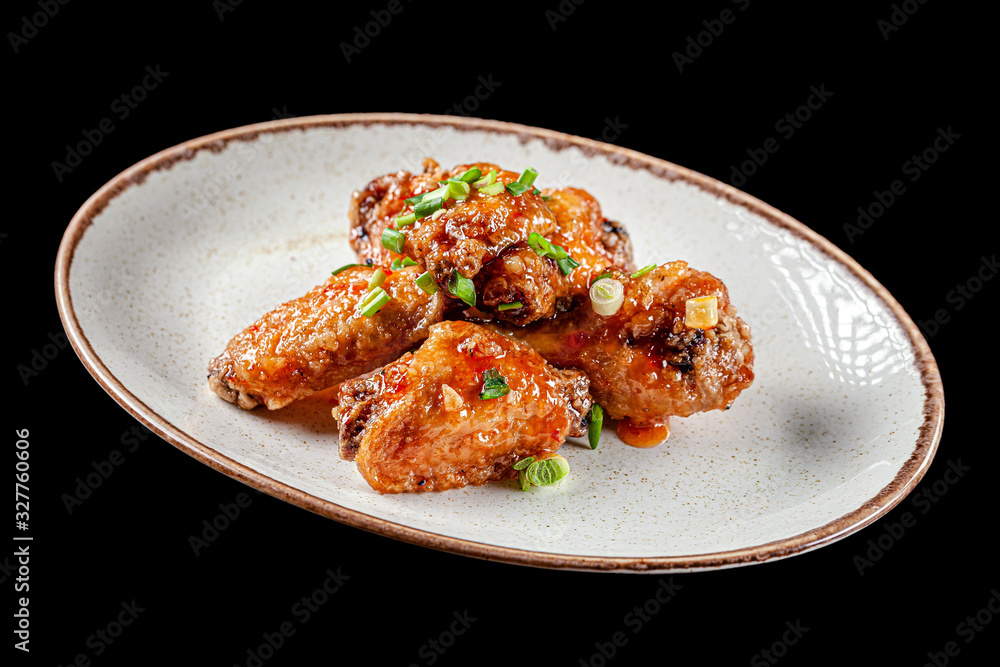 American cuisine. Fried chicken wings with icing and green onions. Serving dishes in a restaurant in a white plate. A glass of light beer on the table. background image, copy space American cuisine. Fried chicken wings with icing and green onions. Serving dishes in a restaurant in a white plate. A glass of light beer on the table. background image, copy space