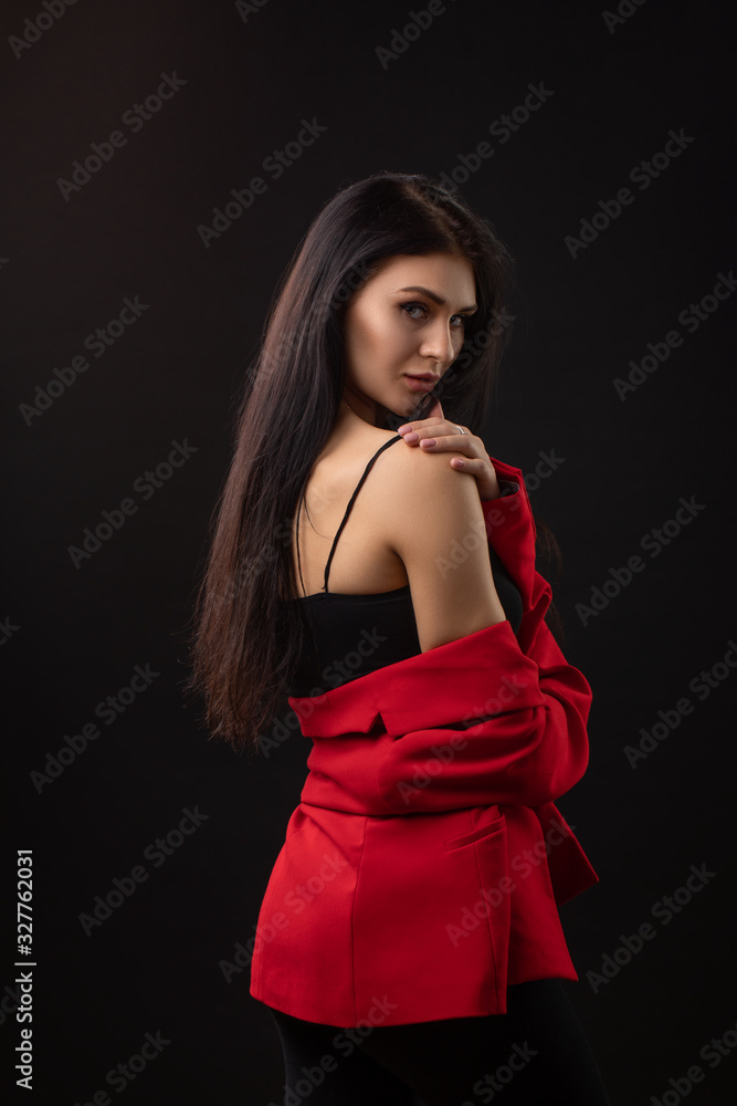 Portrait of a beautiful fashionable brunette woman in a red business suit on black background Portrait of a beautiful fashionable brunette woman in a red business suit on black background