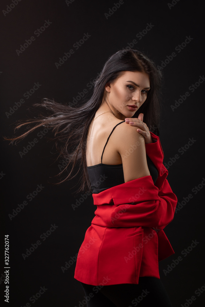 Portrait of a beautiful fashionable brunette woman in a red business suit on black background Portrait of a beautiful fashionable brunette woman in a red business suit on black background