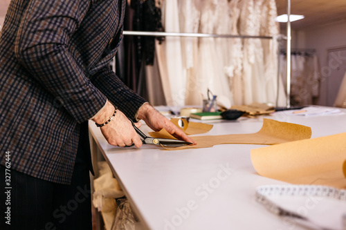 Tailor working at studio cutting fabric, detail of hand with scissors