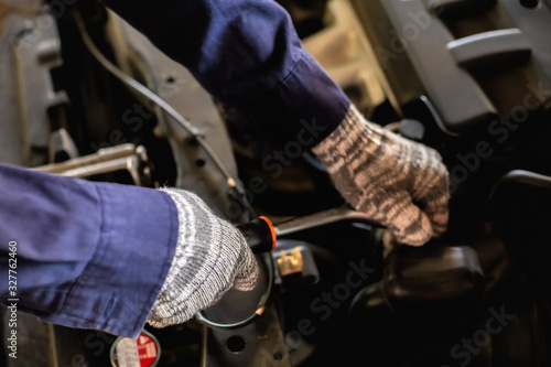 Close up. Hand holding auto mechanic using a wrench and screwdriver to working service car in garage.