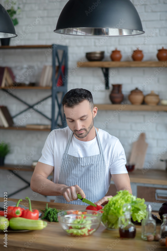 Attentive man chopping pepper on a cutting board. Attentive man chopping pepper on a cutting board.