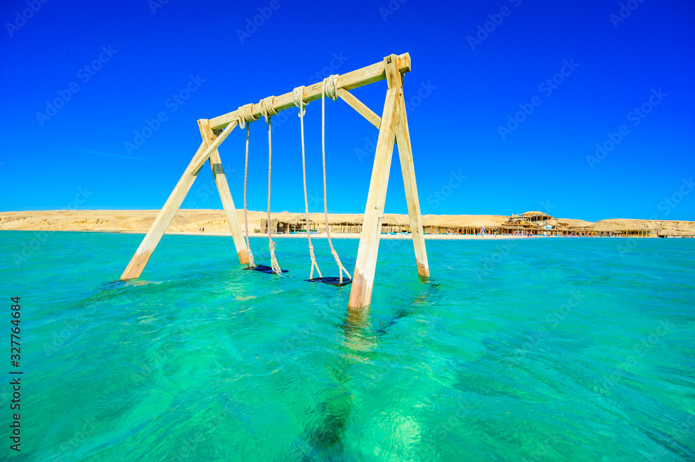 Swing in crystal clear azure water - Orange Bay Beach with white beach - paradise coastline of Giftun island, Mahmya, Hurghada, Red Sea, Egypt Swing in crystal clear azure water - Orange Bay Beach with white beach - paradise coastline of Giftun island, Mahmya, Hurghada, Red Sea, Egypt