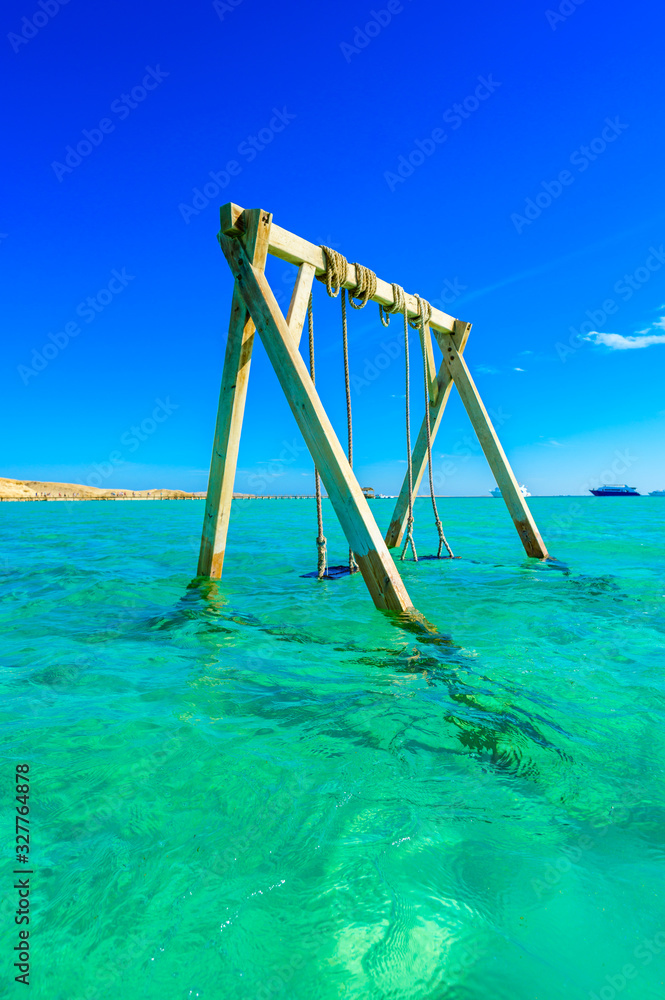 Swing in crystal clear azure water - Orange Bay Beach with white beach - paradise coastline of Giftun island, Mahmya, Hurghada, Red Sea, Egypt Swing in crystal clear azure water - Orange Bay Beach with white beach - paradise coastline of Giftun island, Mahmya, Hurghada, Red Sea, Egypt