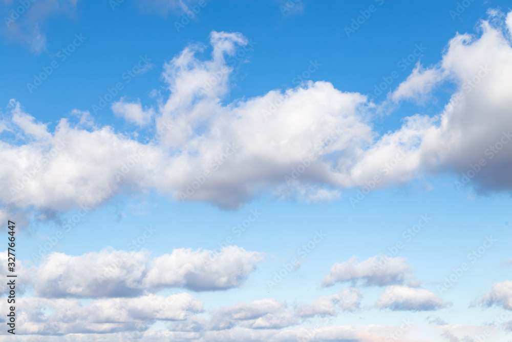 Snow-white fluffy clouds against the blue sky. Light and shadow.