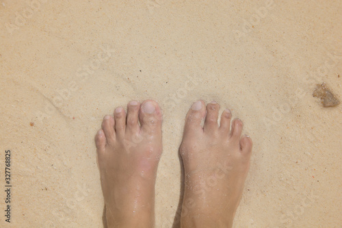 Asian female wet bare foot standing on the beach sand for relaxing, beach of Krabi, Thailand.