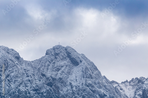 Giewont Mountain in polish Tatra Mountains covered with snow under cloudy sky © Alex White