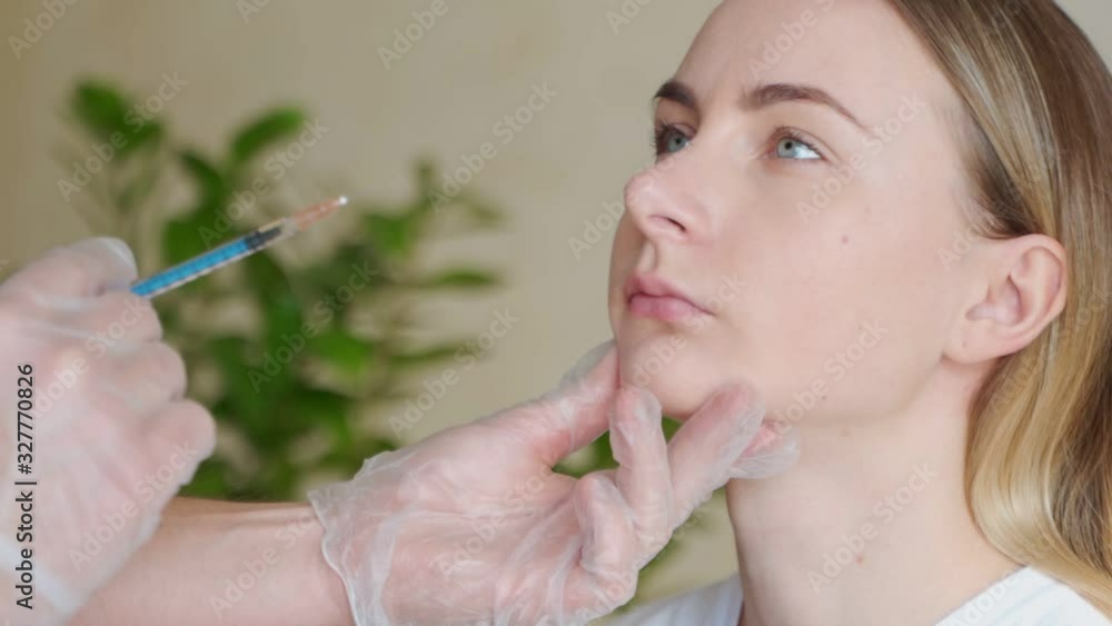 Cropped close-up of a beautiful young woman getting lip injections by professional cosmetologist. Female client getting lip augmentation procedure at beauty salon Cropped close-up of a beautiful young woman getting lip injections by professional cosmetologist. Female client getting lip augmentation procedure at beauty salon