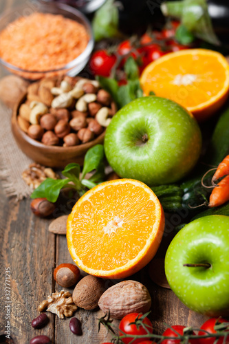 Concept of healthy vegan food, clean eating. On wooden background: vegetables, fruits, nuts, beans, lentils. Ripe seasonal product for clean meal. Copy space for text