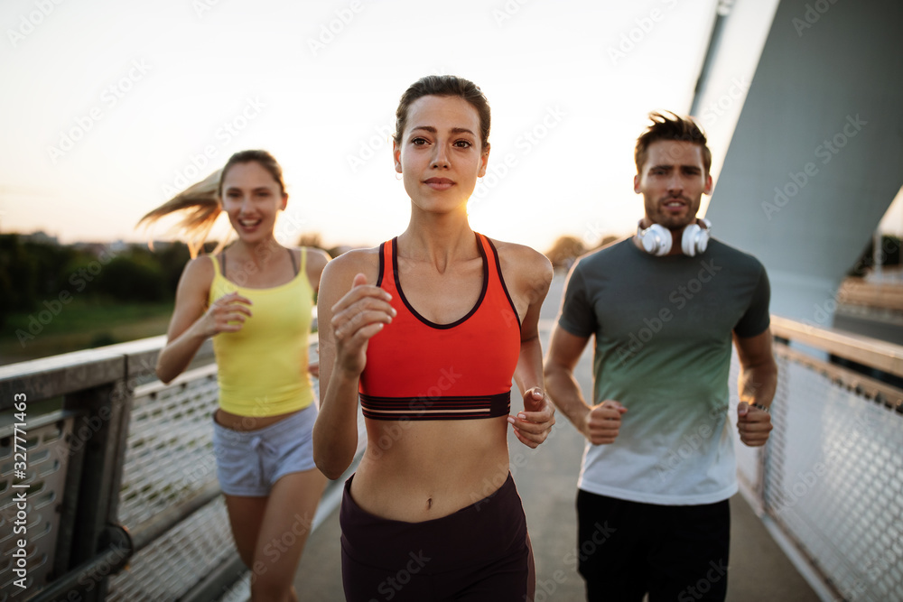 Athletic fit people exercising and running together outdoors