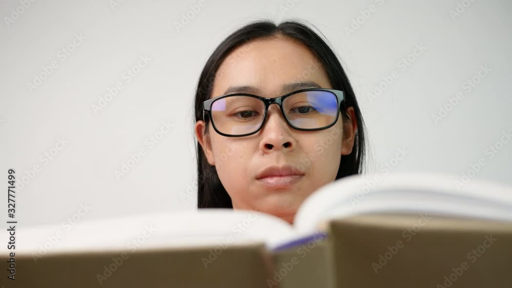 Close up of Woman's hand turning pages of a book and moves her fingers along the page while reading at library. Selective focus. Close up of Woman's hand turning pages of a book and moves her fingers along the page while reading at library. Selective focus.