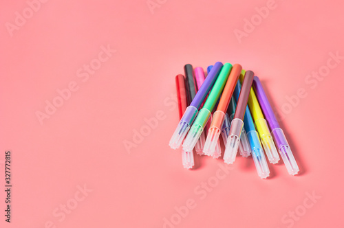 Heap of multi colored felt pens lies on pink desk in kindergarten. Сoncept of parenting and education of children. Copy space