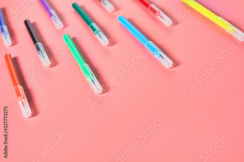 Rows of multi colored felt pens lies on pink desk in kindergarten. Сoncept of parenting and education of children. Copy space