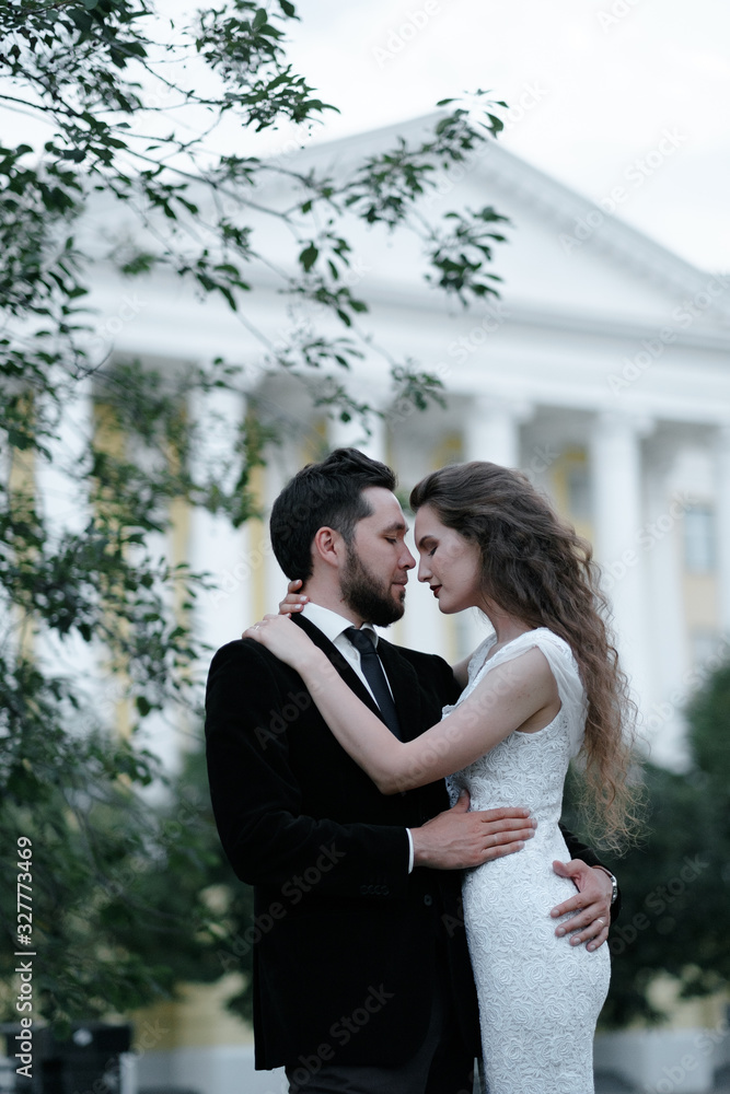 Beautiful wedding couple of newlyweds - red-haired young bride in a white dress and a bearded groom in a black suit. Amazing smiling wedding couple. Pretty bride and stylish groom. Beautiful wedding couple of newlyweds - red-haired young bride in a white dress and a bearded groom in a black suit. Amazing smiling wedding couple. Pretty bride and stylish groom.