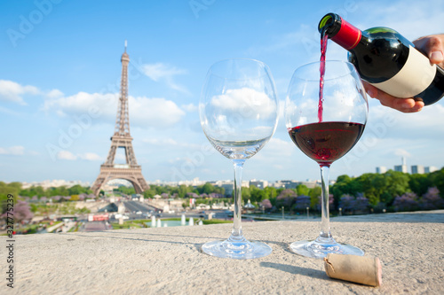 Photography Sunny view of two glasses and a fresh bottle of red wine overlooking the Eiffel