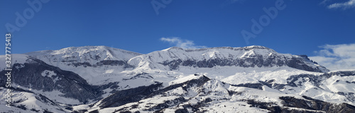 Panorama of high snowy mountains and blue sky with clouds at sun winter day © BSANI