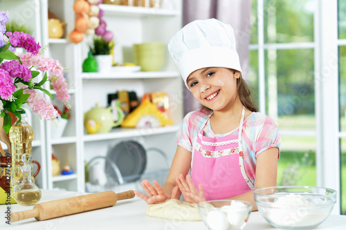 Cute girl making dough in the kitchen