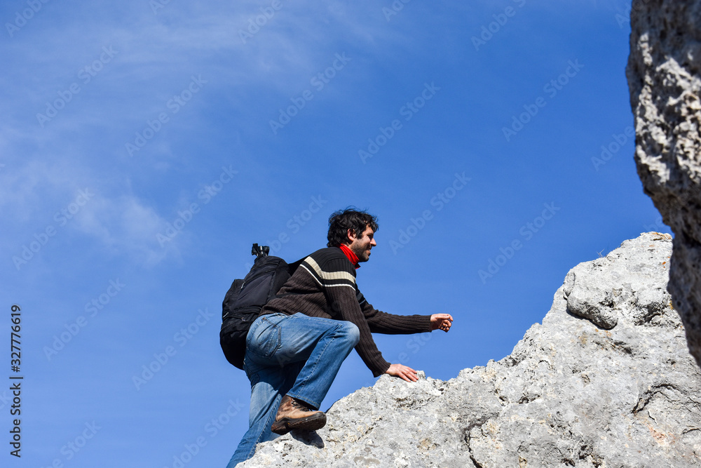 Young hiker climbing up mountain cliff. Climber enjoy in mountains in spring Young hiker climbing up mountain cliff. Climber enjoy in mountains in spring