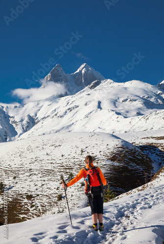 a girl with backpack is in the mountains in winter