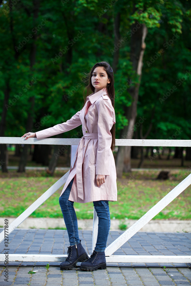 Portrait of a young brunette girl in pink coat on a background of autumn park Portrait of a young brunette girl in pink coat on a background of autumn park