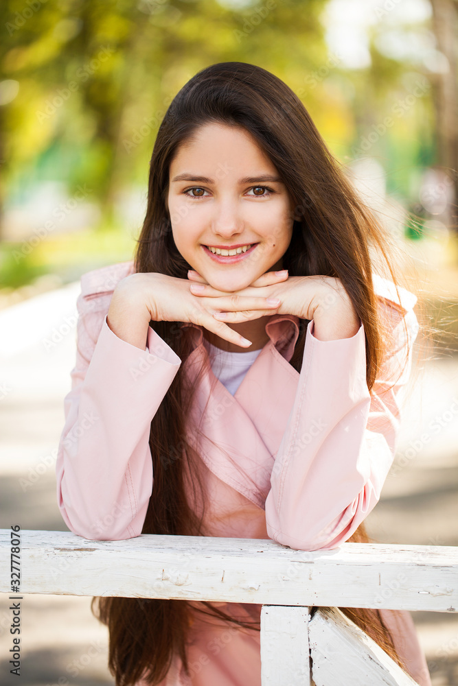 Portrait of a young brunette girl in pink coat on a background of autumn park Portrait of a young brunette girl in pink coat on a background of autumn park