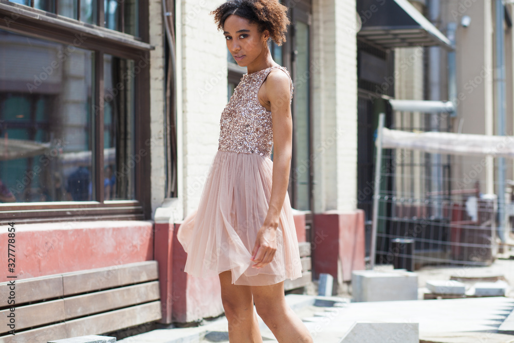 Street fashion. Portrait of an African young woman in pink dress Street fashion. Portrait of an African young woman in pink dress
