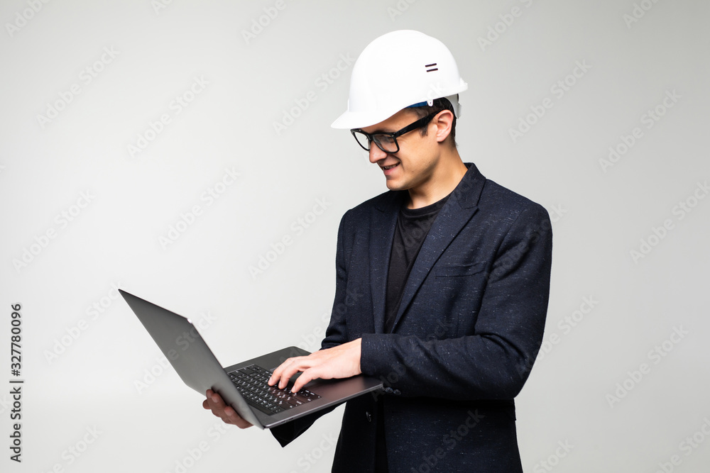 Smart young architect wearing glasses and yellow safety helmet which hands holding a laptop to check his planned work Smart young architect wearing glasses and yellow safety helmet which hands holding a laptop to check his planned work