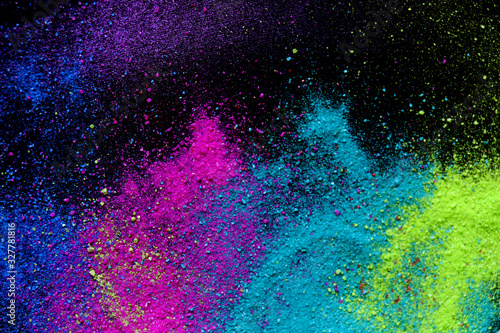Multi-colored powder sprayed on black background. Holi celebration with copy space.