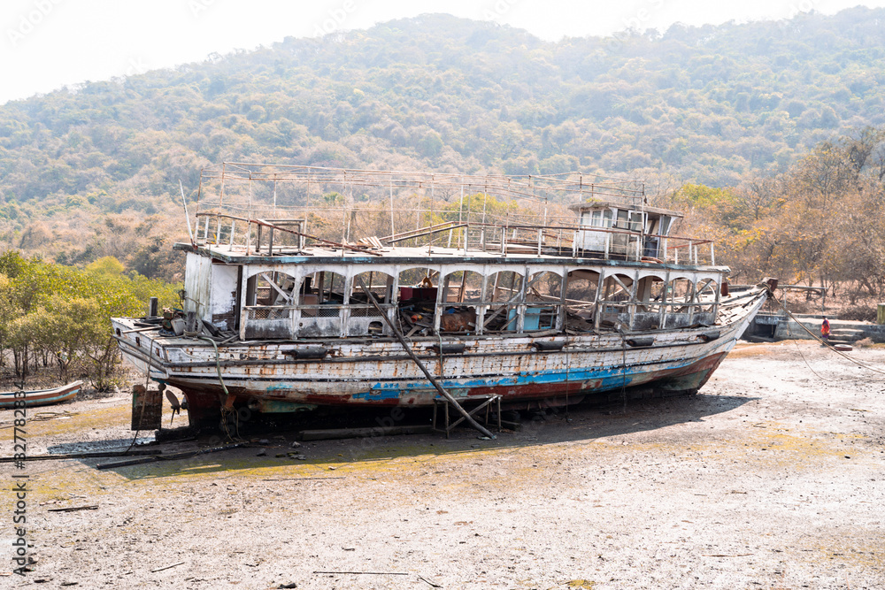 Old, weathered abandoned boat sits in a marsh at low tide on Elephanta Island in Mumbi, India