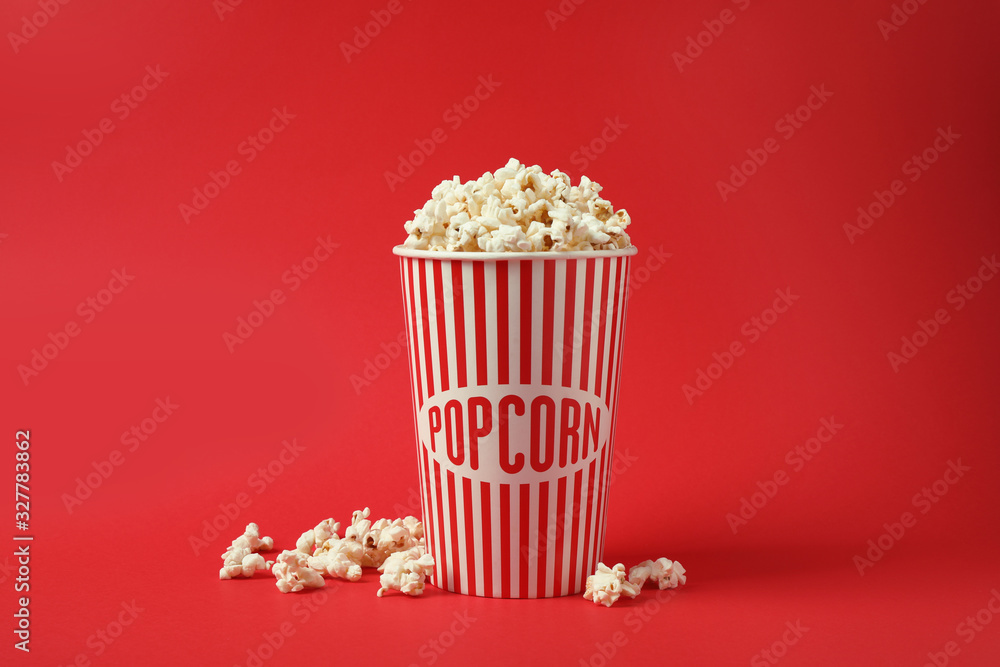 Delicious popcorn in paper cup on red background Delicious popcorn in paper cup on red background