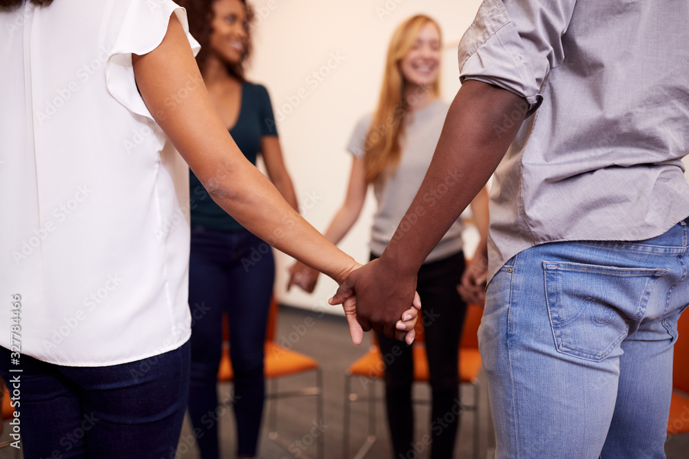 Multi-Cultural Group Of Men And Women Joining Hands At Mental Health Group Therapy Meeting Multi-Cultural Group Of Men And Women Joining Hands At Mental Health Group Therapy Meeting