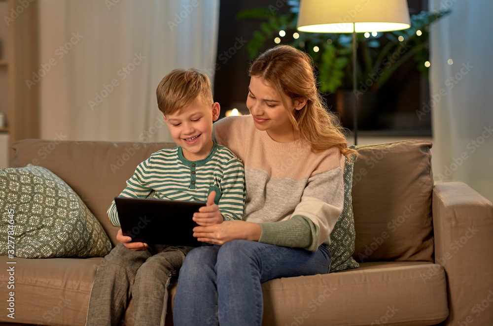 family, technology and people concept - happy mother and little son sitting on sofa and using tablet pc computer at home family, technology and people concept - happy mother and little son sitting on sofa and using tablet pc computer at home