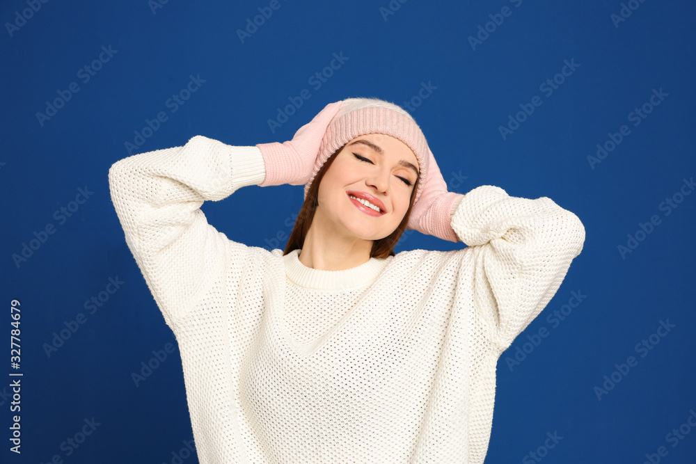 Young woman wearing warm sweater, gloves and hat on blue background. Winter season Young woman wearing warm sweater, gloves and hat on blue background. Winter season