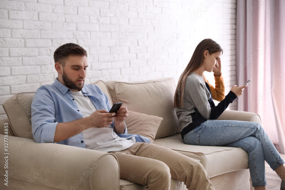 Obraz premium Couple addicted to smartphones ignoring each other at home. Relationship problems