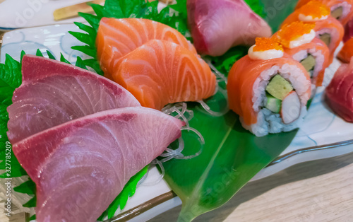 Japanese food set served on white plate. Salmon sushi and sashimi on restaurant table. Fresh raw fish meat sliced and Japan vinegared rice rolls with seafood and vegetables. Healthy Japanese food.