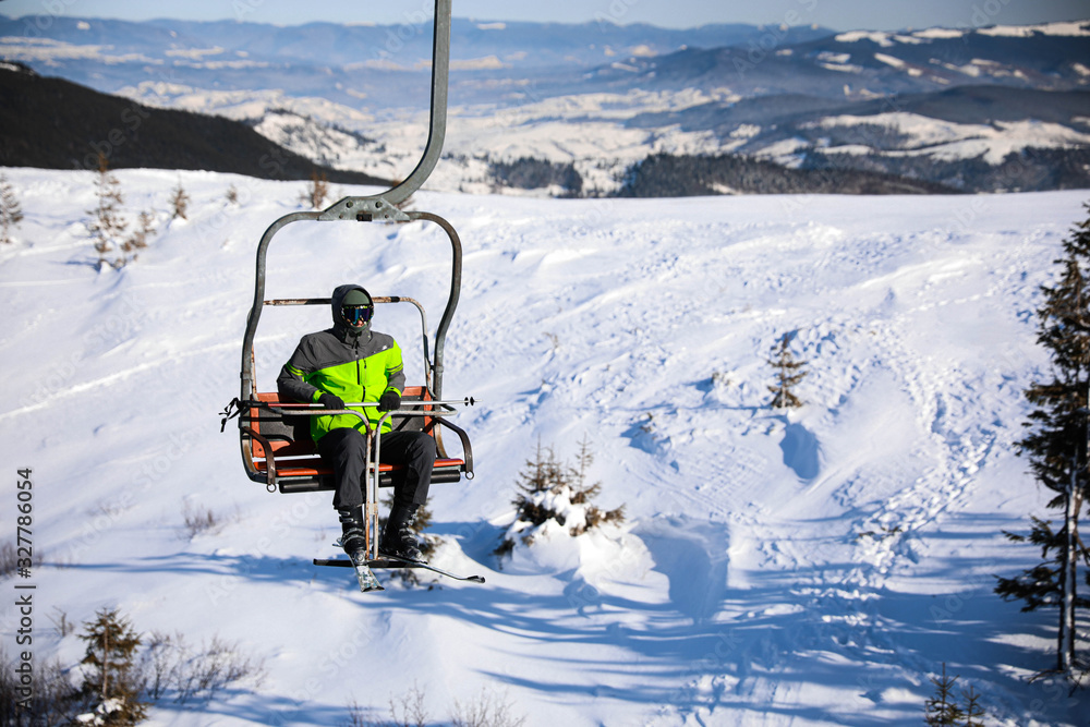 Man using chairlift at mountain ski resort, space for text. Winter vacation